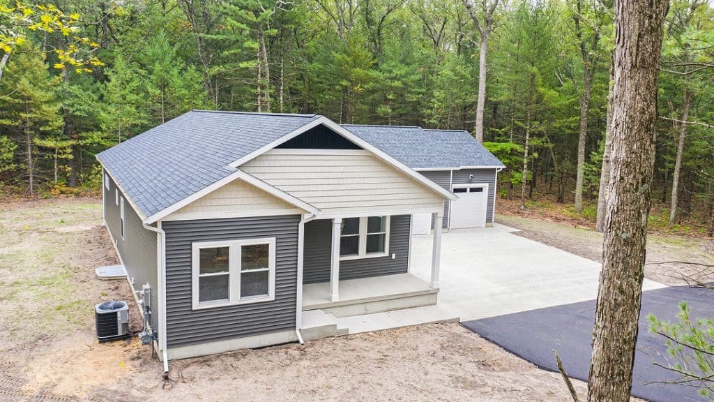 Newly built modern home with gray siding and white trim in a wooded area.