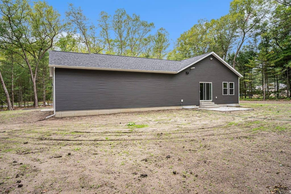 Newly built modern home with gray siding and large backyard.