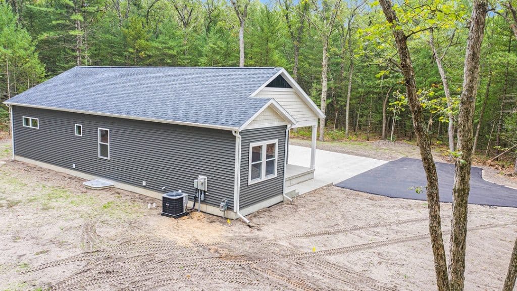 Newly built custom home by BuildWest with gray siding and a spacious driveway.