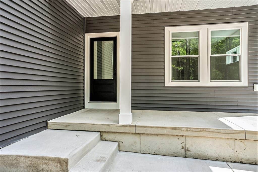 Contemporary house entrance with black door and white-framed window.