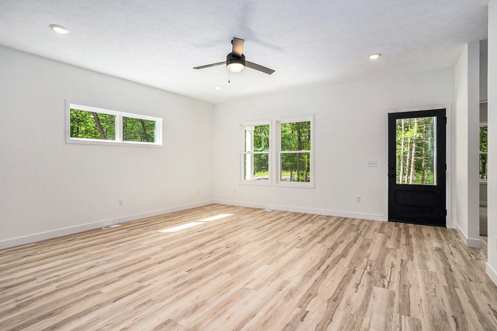 Bright living room with large windows and wood flooring in a custom home.