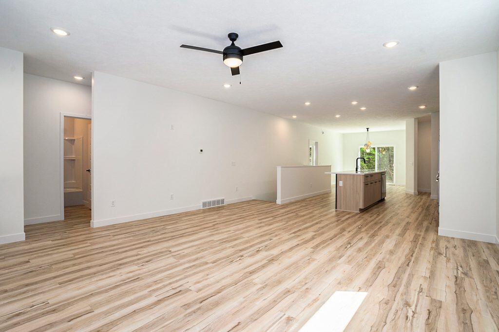 Bright open-concept living room with hardwood floors and ceiling fan.