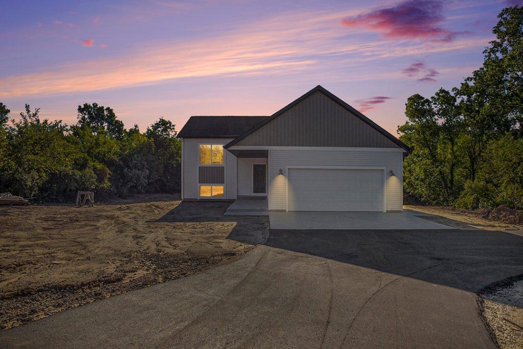 New custom home with modern design and driveway at sunset.