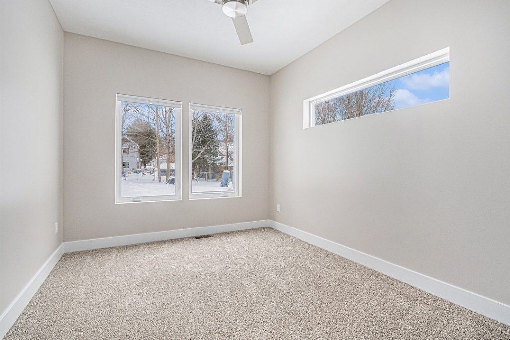 Bright bedroom with large windows and neutral decor for a modern home.