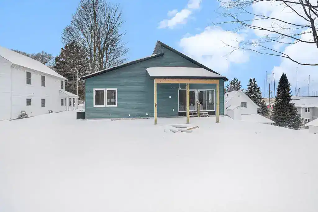 New custom-built home with blue siding in a snowy setting.