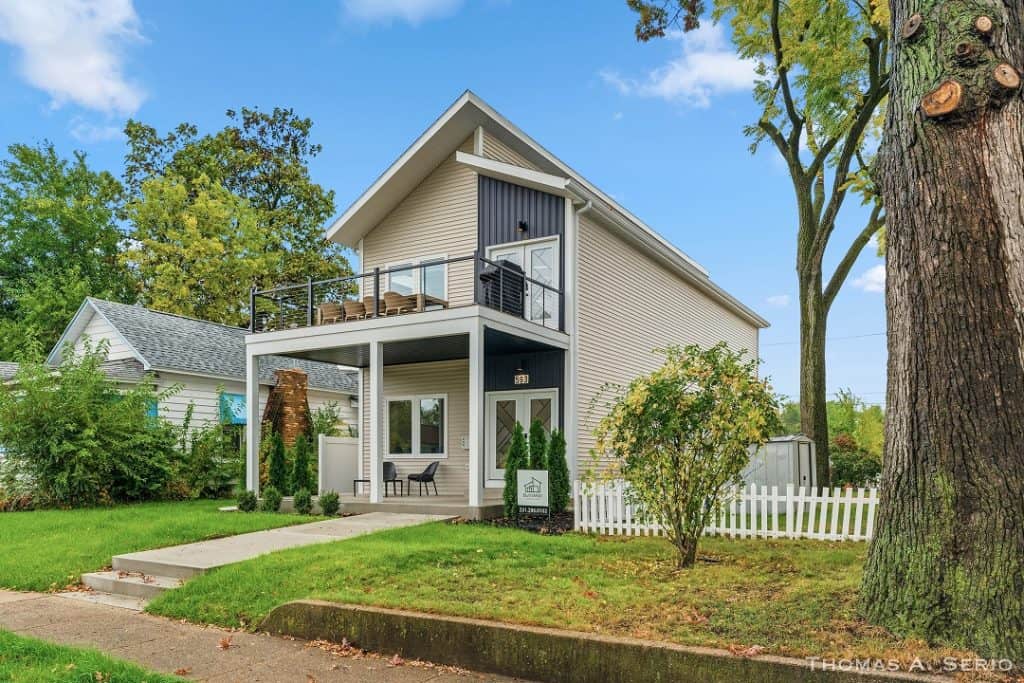 Contemporary two-story home with balcony and lush front yard.