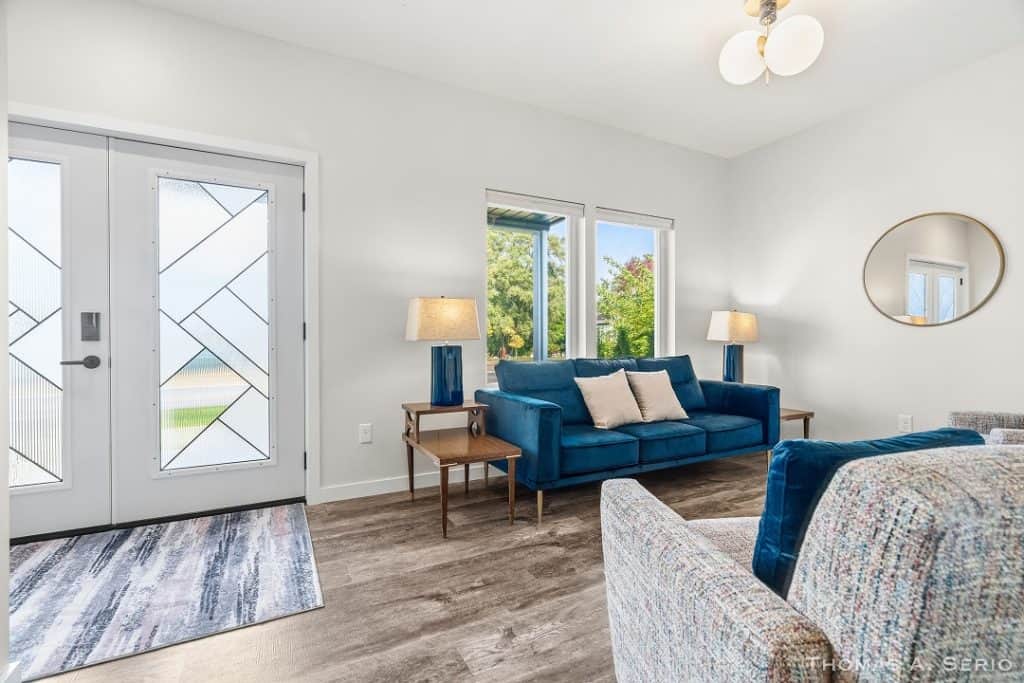 Bright living room with blue sofa, large windows, and contemporary decor.