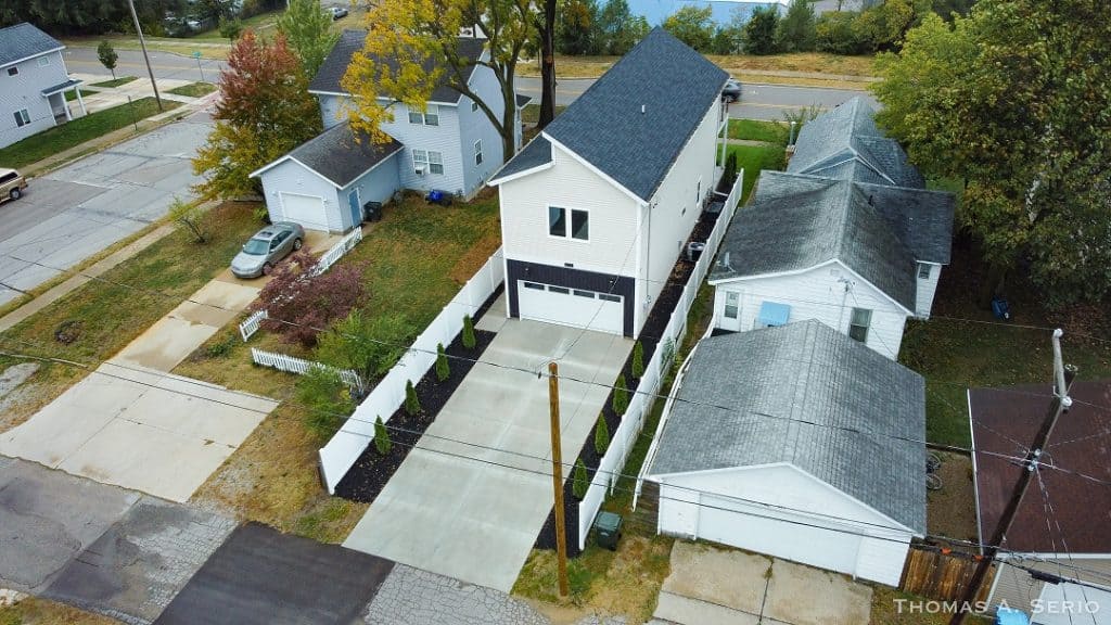 Contemporary white house with driveway and fenced backyard in suburban neighborhood.