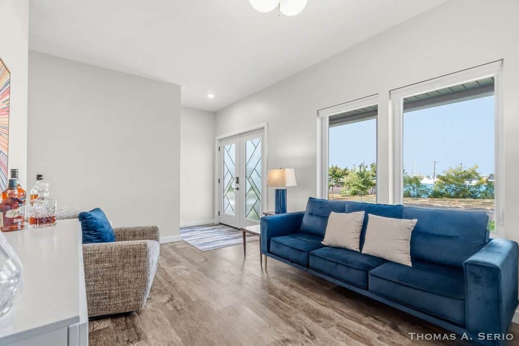 Bright modern living room with blue sofa and large windows.