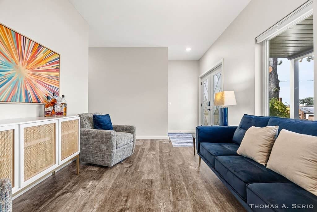 Bright living room with blue and gray sofas, artwork, and large window with outdoor view.