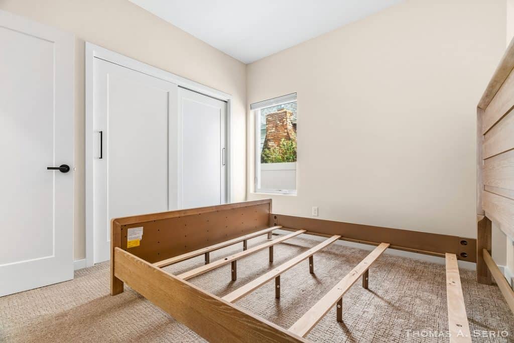 Bedroom with new wooden bed frame and window view.