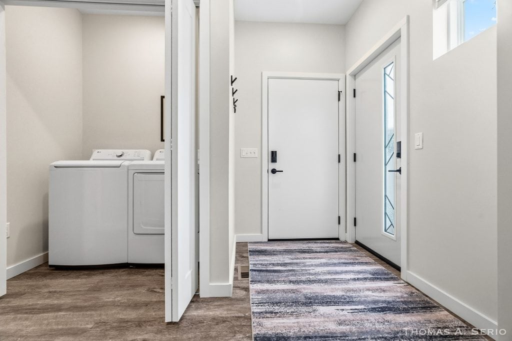 Bright laundry room and entryway with white walls and modern design.