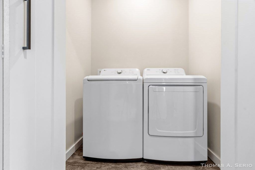 Clean laundry room with white washer and dryer in a new build home.