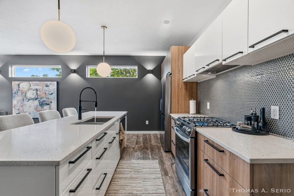 Contemporary kitchen with white cabinets, black backsplash, and wooden accents.