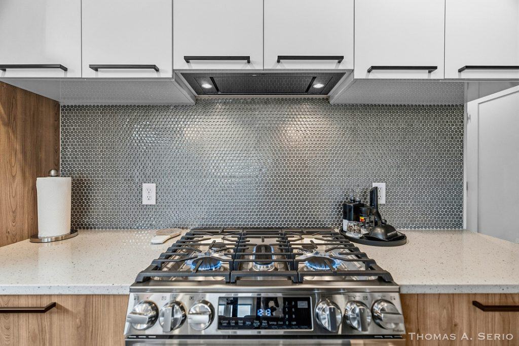 Contemporary kitchen featuring a gas stove, sleek cabinets, and a textured backsplash.
