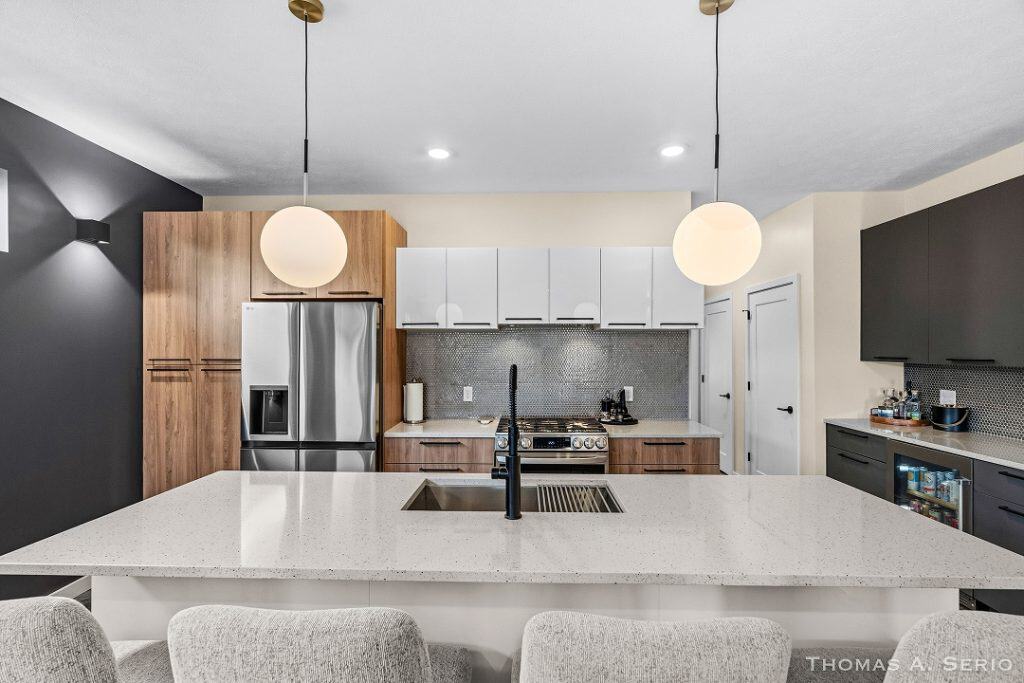 Contemporary kitchen with white cabinets, gray backsplash, and island with seating.