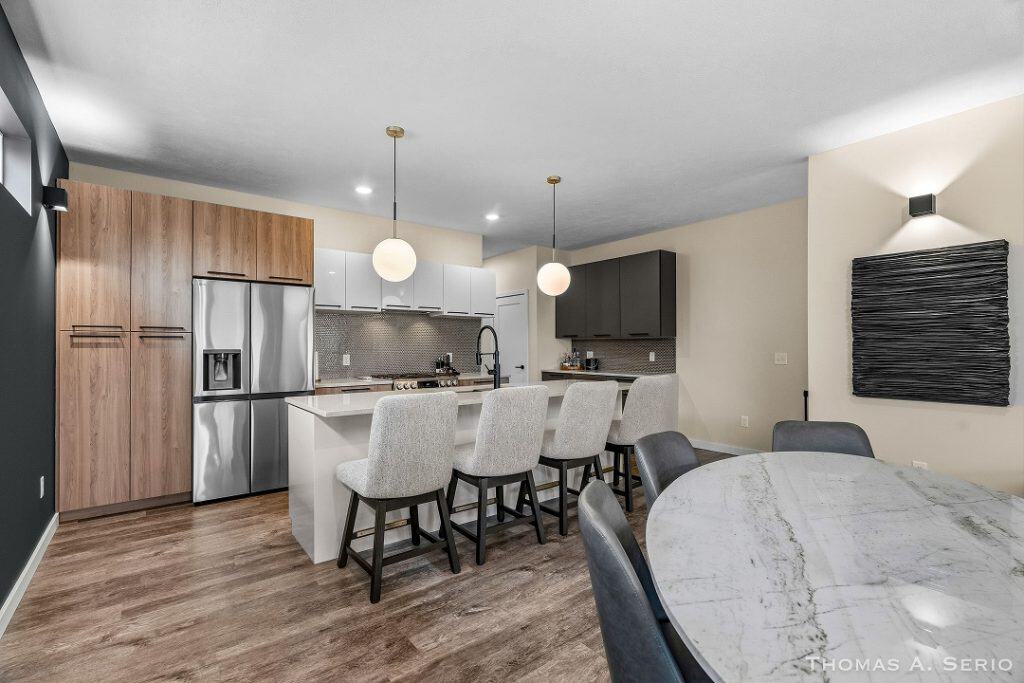 Contemporary kitchen with island, bar stools, and dining table in a new home.