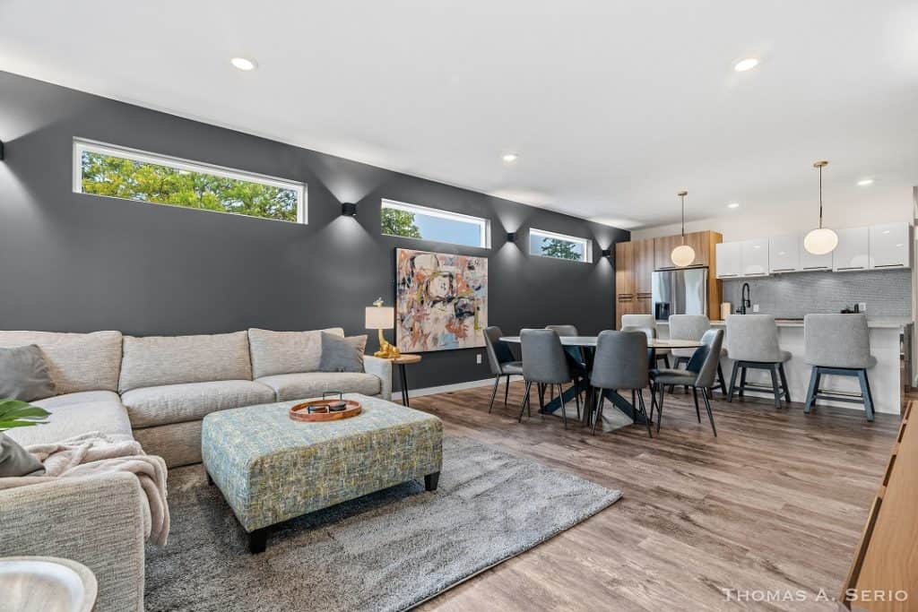 Spacious modern living room with gray walls and open kitchen area.