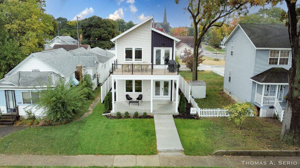 Contemporary white two-story house with deck and backyard in a suburban neighborhood.