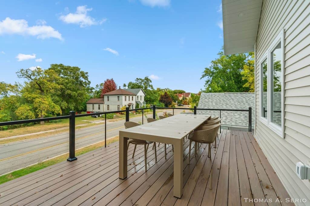 Balcony with outdoor dining table overlooking neighborhood and trees.