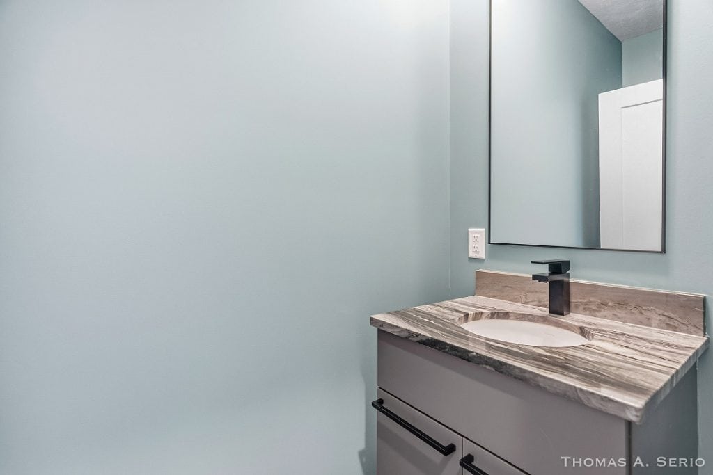 Contemporary bathroom vanity with marble countertop and black faucet.