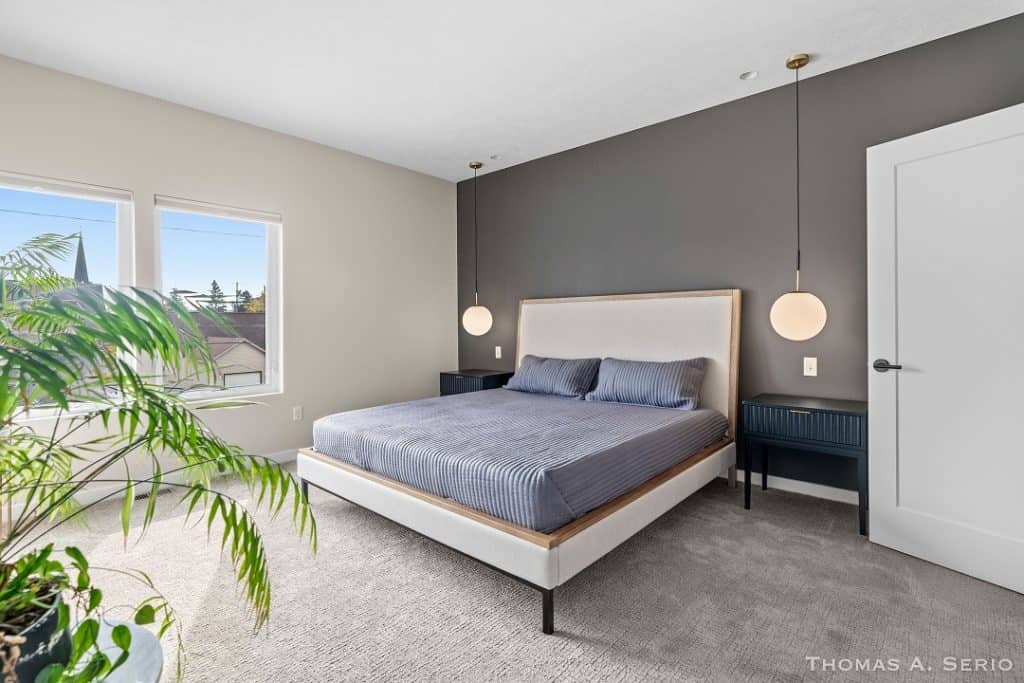 Contemporary bedroom with gray accent wall, large bed, and natural light.