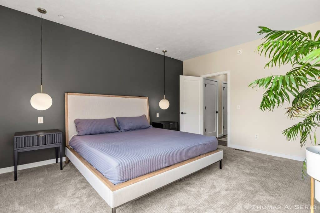 Contemporary bedroom with dark accent wall, minimalist furniture, and natural light.