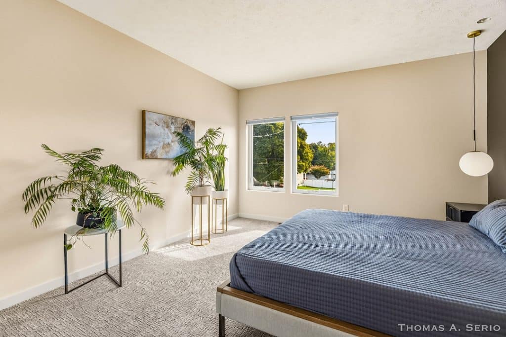 Bright bedroom with large windows, minimalist decor, and indoor plants.