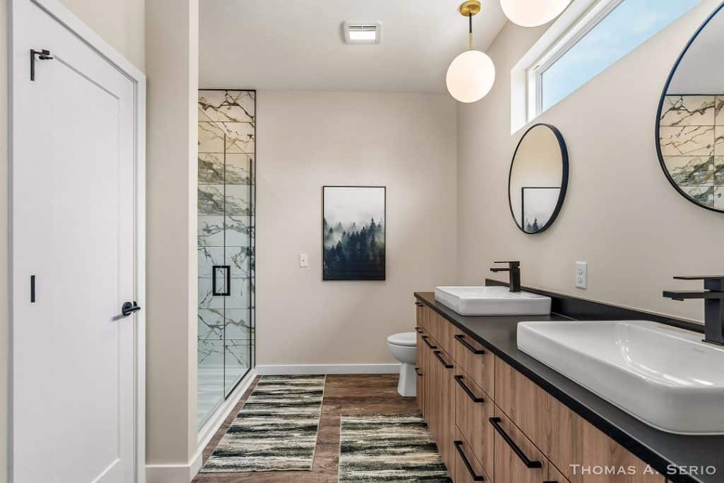 Contemporary bathroom with dual sinks, large mirror, and walk-in shower.