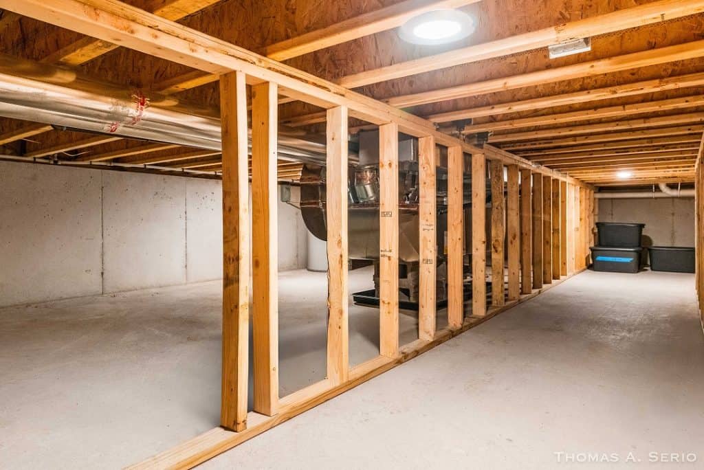 Unfinished basement with wooden framing and concrete floor in a new home.