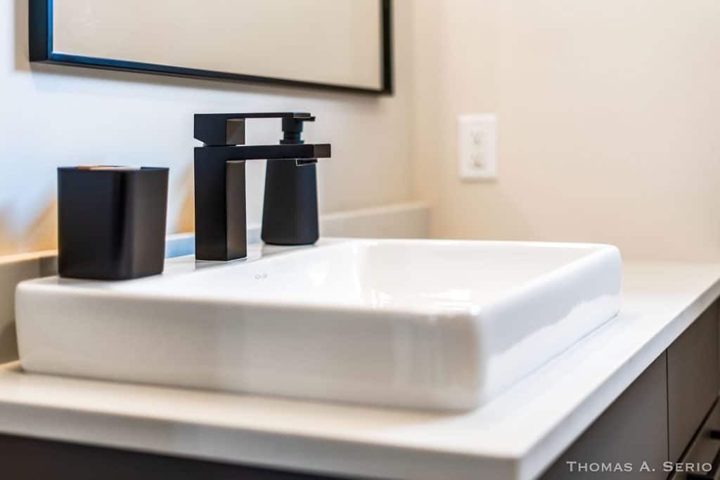 Contemporary bathroom sink with black faucet and accessories in a modern home.