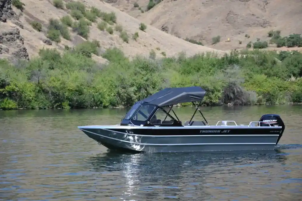Camp and Cruise Thunder Jet 205 Rush boat on water with scenic background.