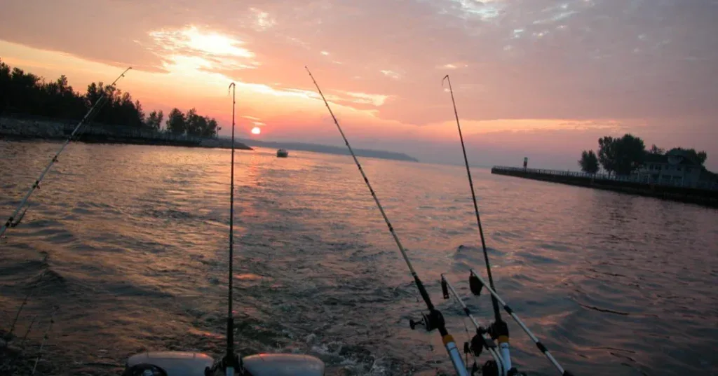 Serene sunset with fishing rods on calm water at Camp & Cruise.