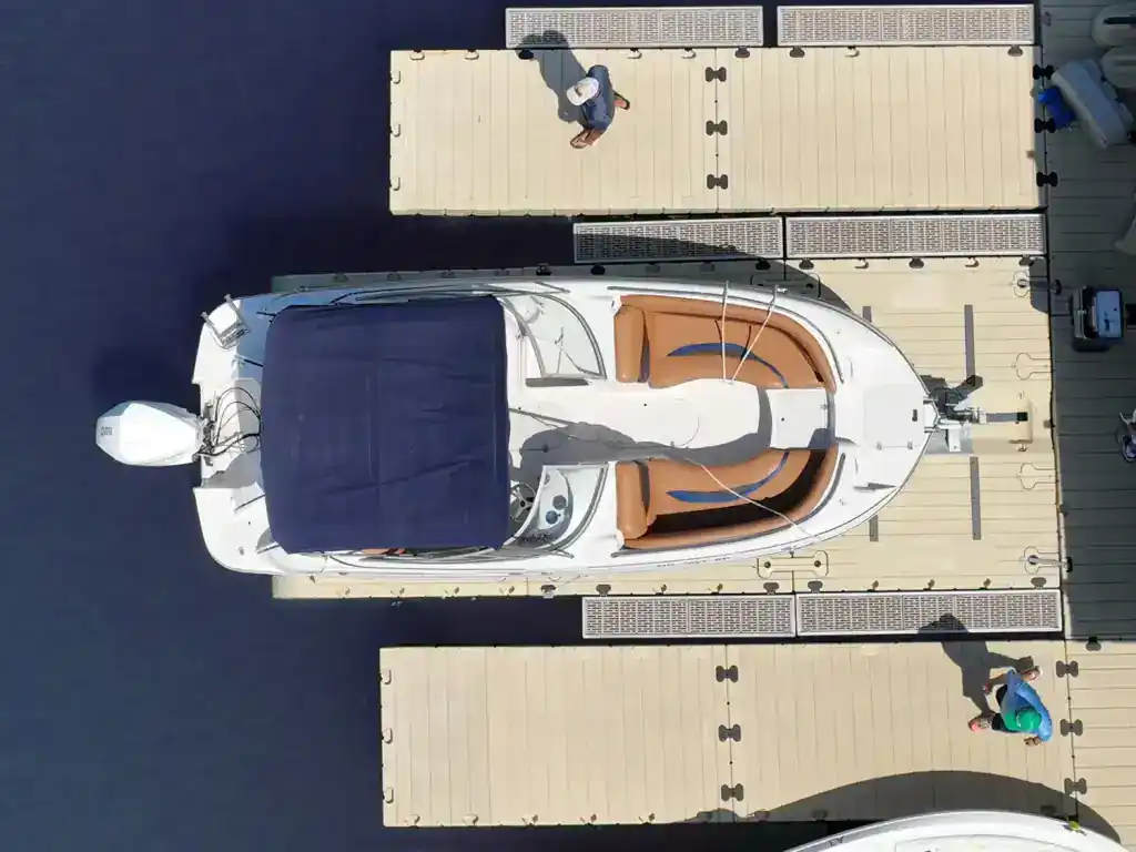 High-angle view of a white yacht on a flatbed trailer at Camp & Cruise dealership.