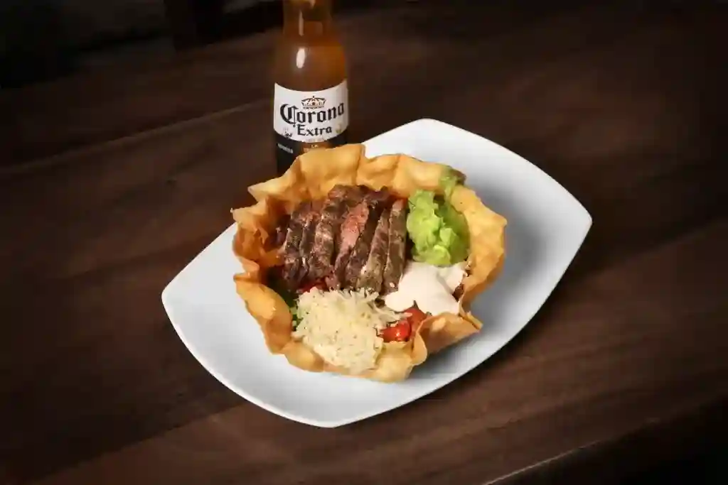 Juicy grilled steak served with rice, guacamole, and salsa on a white plate.