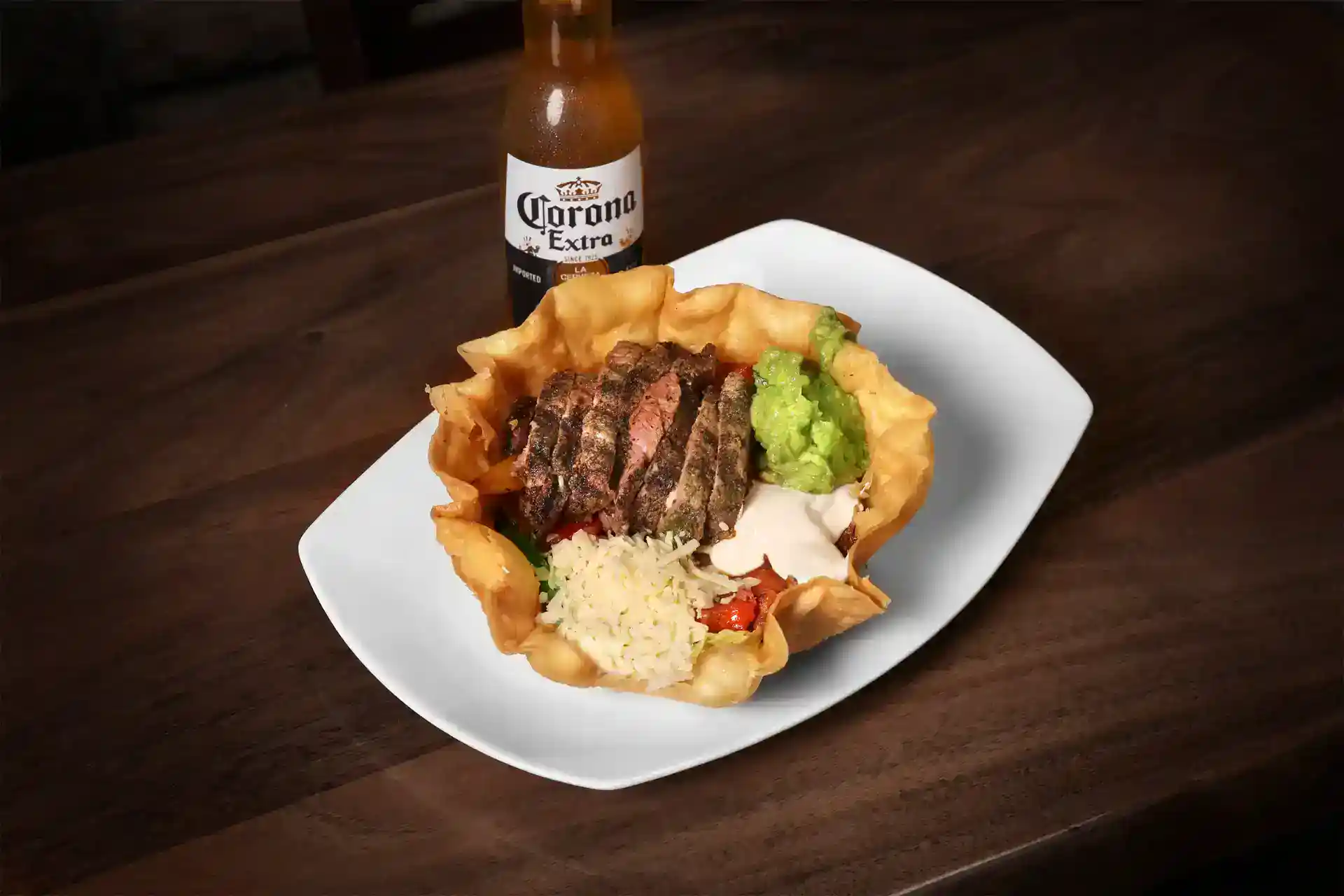 Juicy grilled steak served with rice, guacamole, and salsa on a white plate.