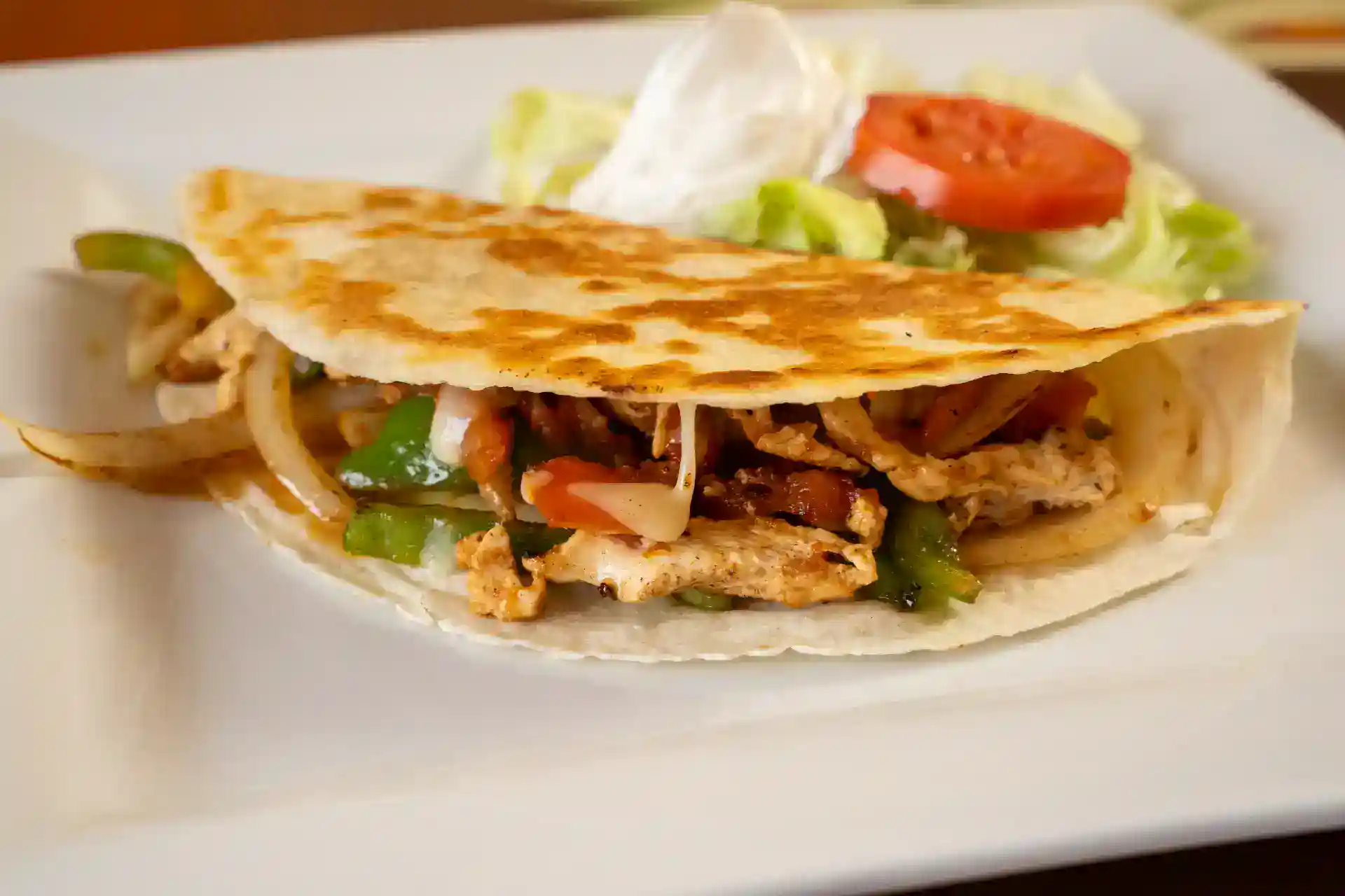 Delicious chicken taco with vegetables and fresh salad on a white plate.