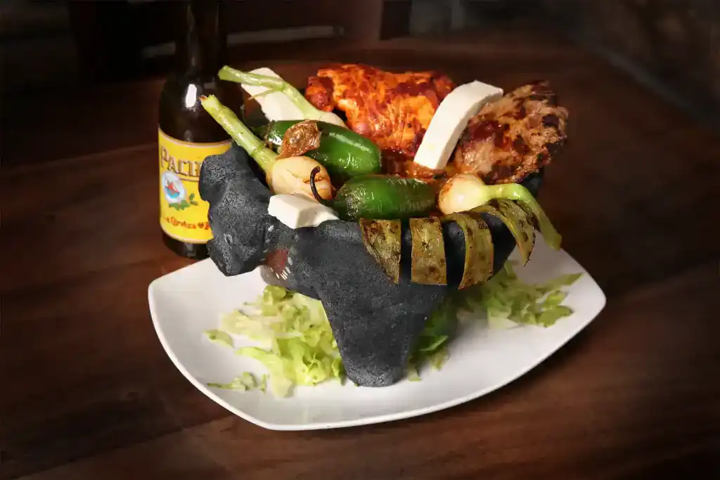 Authentic Mexican dish with grilled meats, peppers, and vegetables served in a traditional stone bow.