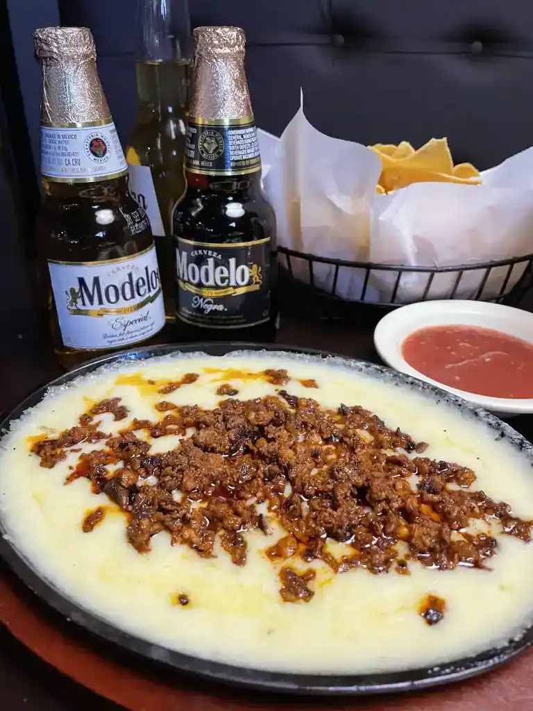 Traditional Mexican dish with seasoned ground beef over creamy mashed potatoes, served with salsa an.