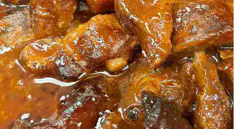 Close-up of hearty soul food stew with tender meat and rich sauce, showcasing traditional Southern flavors.