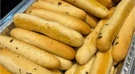 Close-up of freshly baked cornbread sticks with herbs, perfect for soul food meals and catering.