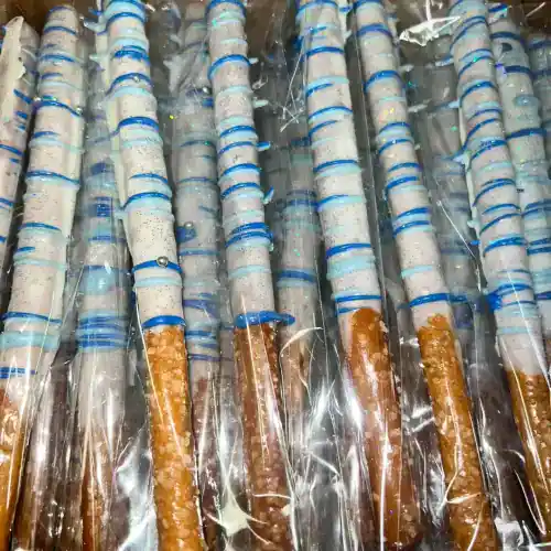 Delicious chocolate-covered pretzel rods decorated with white and blue icing, perfect for celebrations or as a tasty snack.