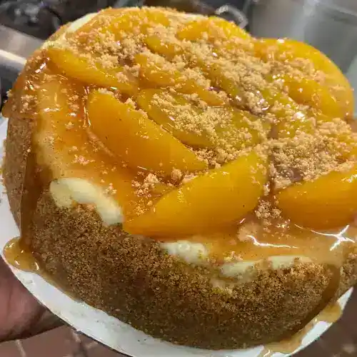 Delicious homemade buttermilk pie topped with fresh peaches and a crumbly streusel, perfect for dessert lovers.