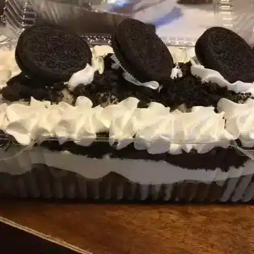 Delicious Lemon Delight cake topped with Oreo cookies, whipped cream, and crushed cookies, perfect for special occasions and dessert lovers.