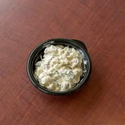 Creamy red skin potato salad in a black container, perfect for Southern comfort food.