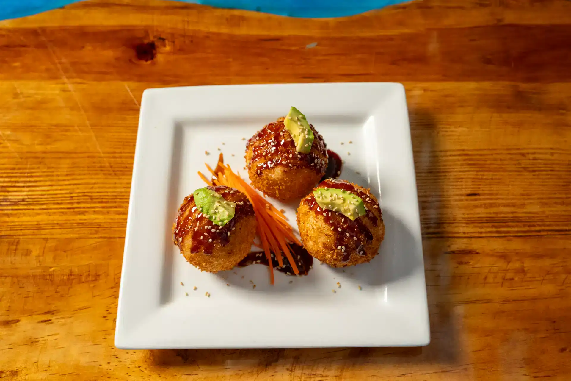 Fried mini balls with green garnish on a white plate.