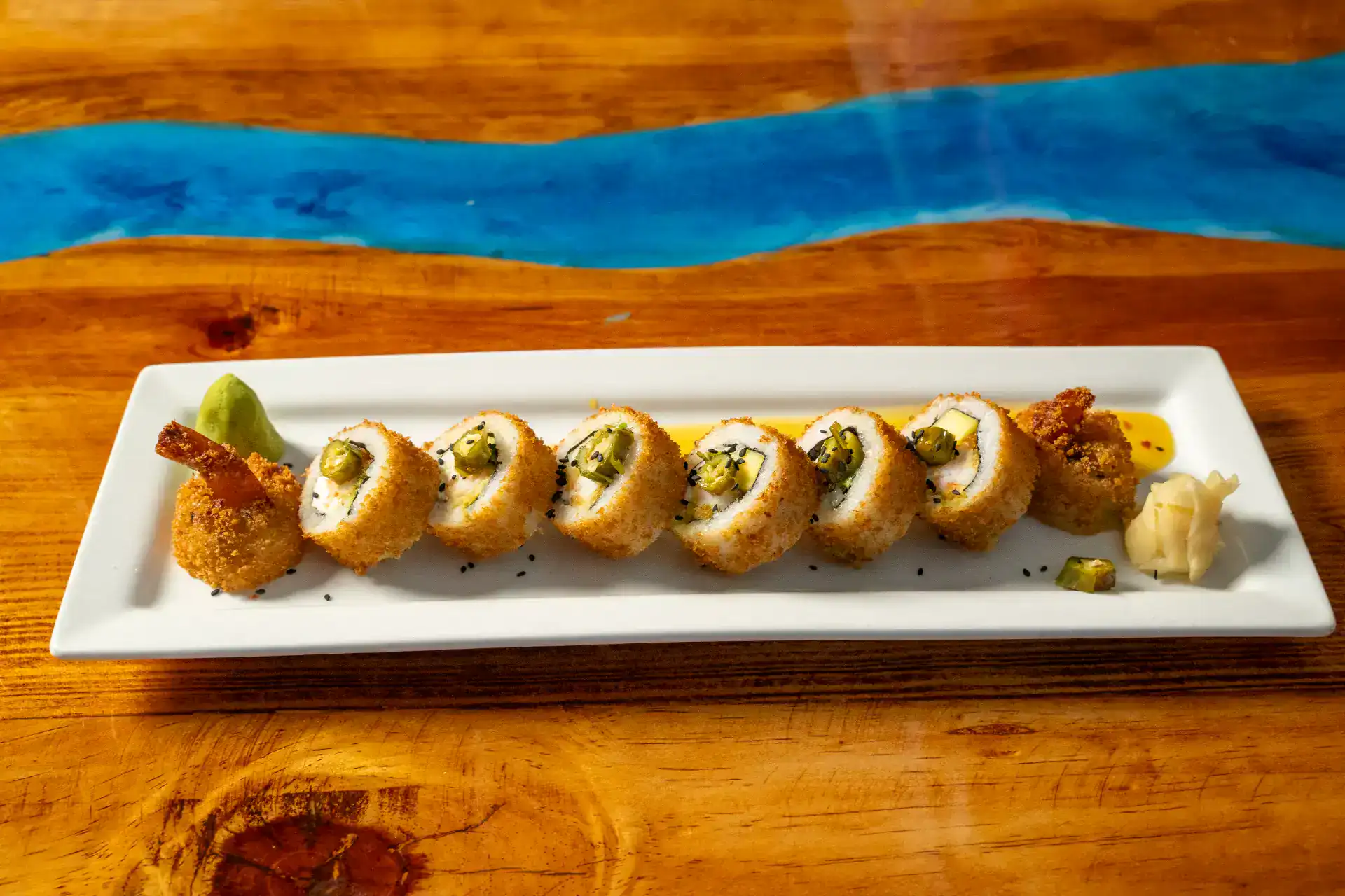 Sushi roll with avocado and fish on a white plate.