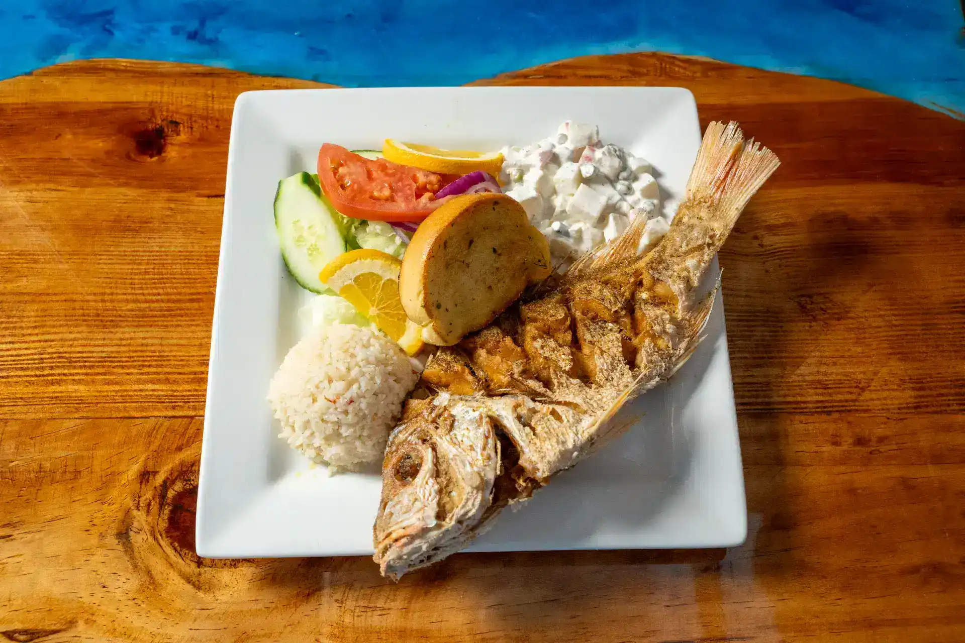Freshly cooked huachinango fish with rice and vegetables on a white plate.