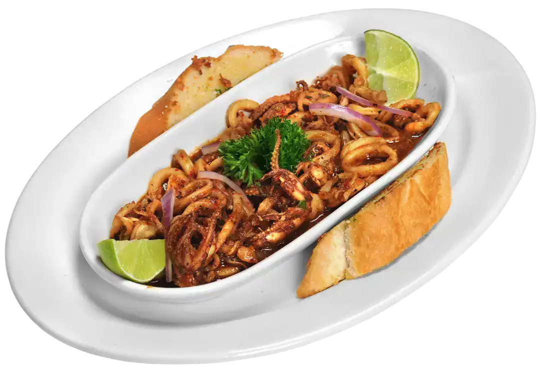 Calamares al Ajillo served with lime and bread on a white plate.