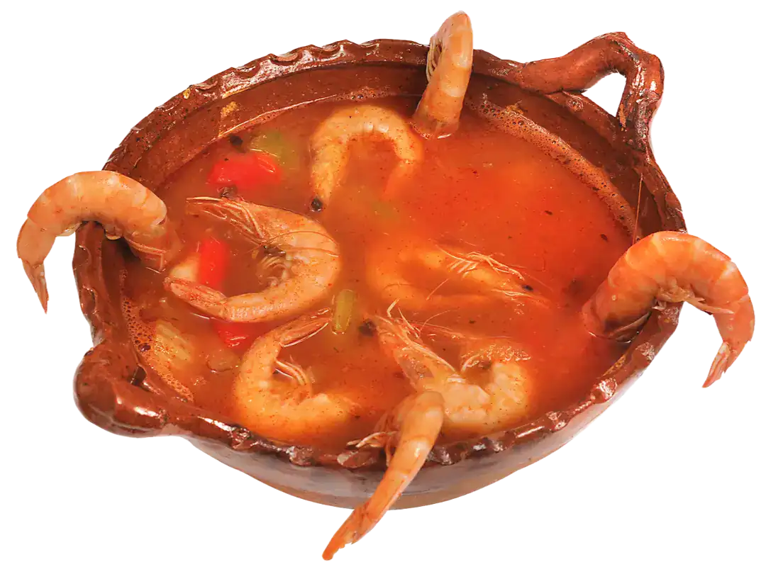 Traditional Caldo de Camarón served in a rustic clay bowl with shrimp and vegetables.